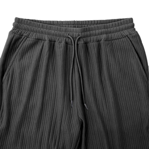 Detail of grey striped trousers showing elastic waistband, drawstring and knit texture
