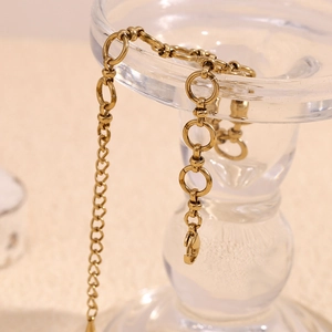 Detail view of a 14K gold plated stainless steel anklet hanging on a glass container