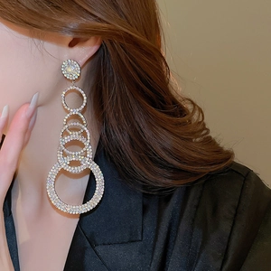 Close-up of sparkling five-layer round tassel earrings with rhinestones on a model