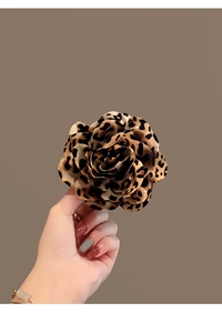 Close-up of a large leopard print flower hair clip with layered petals in soft fabric