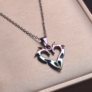 Close-up of rainbow metal heart pendant on chain inside a beige jewelry gift box