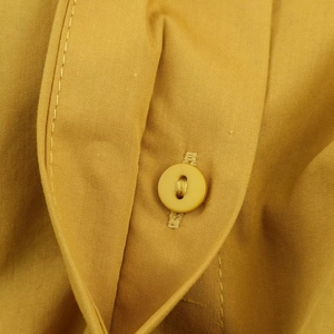 Détail d'une robe midi en popeline jaune moutarde montrant la texture et les boutons