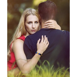 Bracelet en perles œil de tigre bleu au poignet d'un couple en forêt naturelle