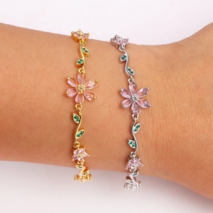 Close-up of pink cherry blossom charm bracelet set in gold and silver finish with crystal