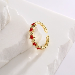 Detail of gold chain-link ring featuring vibrant red enamel star patterns on stone base