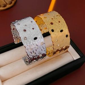 Detail of wide open cuffs with hammered texture and circular cut-outs in gold and silver