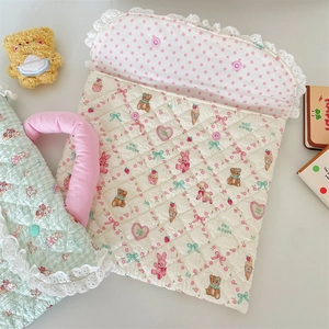 Close-up of quilted laptop sleeve with cute cartoon prints and delicate white lace trim