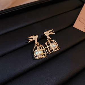 Macro view of bird and cage earrings with crystal inlay and white pearl detail