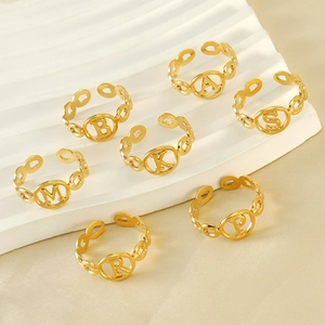 Adjustable 18K gold titanium steel alphabet rings displayed on elegant white wave pedestal