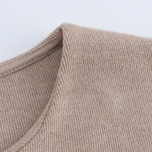 Detailed close-up of khaki knit fabric showing neck and shoulder stitching of the set