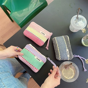 Detailed view of woven mini makeup bags in colorful striped patterns with zipper pulls