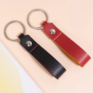 Minimalist leather keychains in black and red with silver metal rings on a pink background
