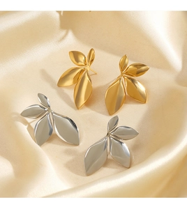Detailed view of gold and silver leaf earrings on elegant champagne satin fabric