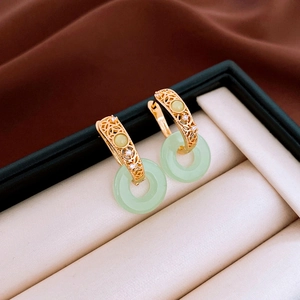 Detail view of jade-like green earrings with gold hollow pattern in a jewelry box