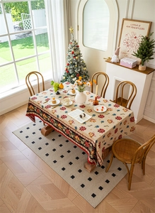 Detail of Christmas tablecloth featuring poinsettia, gold bells and red ribbon patterns