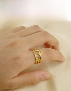 Makro-Detail eines 18K vergoldeten Edelstahlrings mit Stern- und Mondanhängern an der Hand