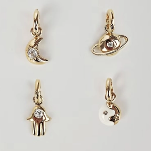Gold plated celestial pendants including moon, Saturn, and Hamsa hand with zircon stones