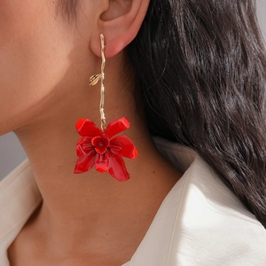 Close-up of vibrant red layered flower earrings with gold hooks on a model's ear