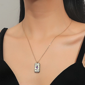 Detail of gold tarot lovers pendant showing a purple heart and L'AMOUREUX engraving