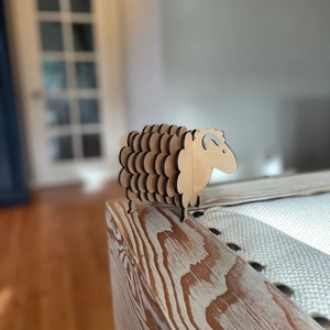 Detail of wooden sheep coaster set with interlocking plywood layers on a desktop