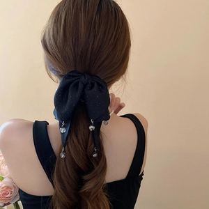 Detail view of black bow hair claw with transparent crystal tassels on wavy brown hair