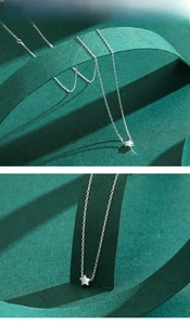 Detailed view of sterling silver star pendant on a fine chain with emerald background