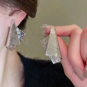 Modern oversized geometric folded silver earrings with textured hammered finish on ear