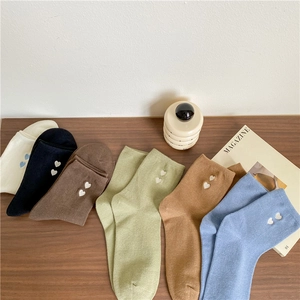 Detail shot of assorted cotton socks with heart embroidery and ribbed cuffs on wood