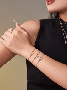 Dettaglio di braccialetti a cuore in oro 18k con zirconi cubici indossati su pelle