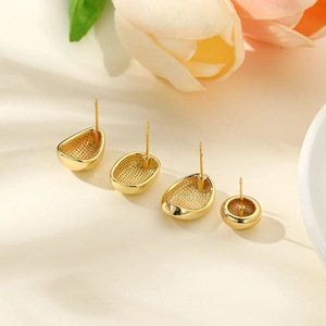 Detailed view of four geometric gold-plated stud earrings on a minimalist cream surface