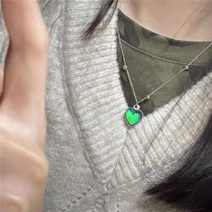 Close-up of a temperature color-changing heart pendant necklace worn by a model