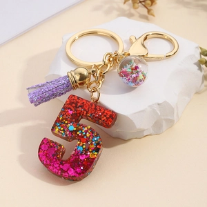 Macro detail of number 5 resin keychain with colorful sequins and purple tassel