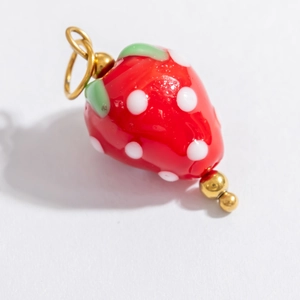 Detailed close-up of a red strawberry glass pendant with 18k gold-plated steel loop
