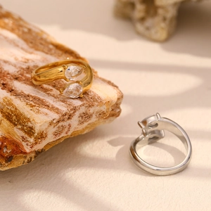 Detail of gold and silver open rings with double pear-shaped cubic zirconia on desert stone