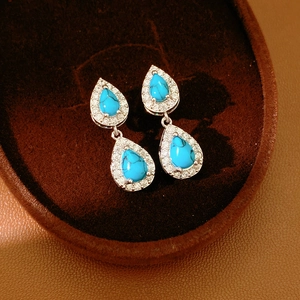 Macro detail of vintage blue stone teardrop earrings with zircon halo in jewelry box