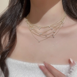 Detail of elegant gold layered necklace with zircon stones and delicate bead chains