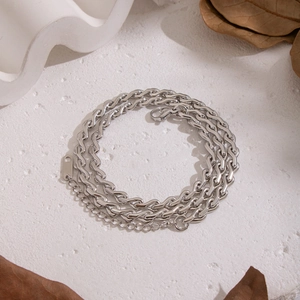 Macro detail of silver-toned layered stainless steel chains on aesthetic white surface