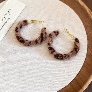 Detail of leopard print faux fur round earrings with gold finish metal hoop clasp