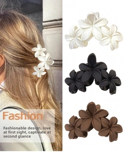 Macro detail of three matte plumeria flower hair claws in white, black and brown colors