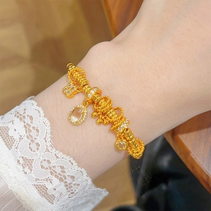 24k gold plated oval gemstone and hollow flower charm bracelet on a model wrist