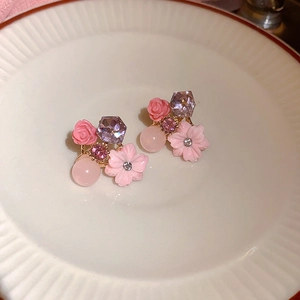 Dettaglio orecchini a fiore in resina rosa con cristalli viola su vassoio ceramico