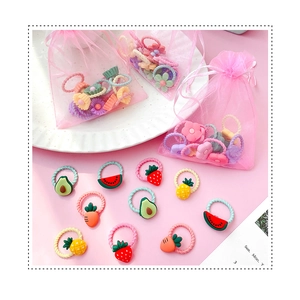 Detail of assorted small baby hair ties with cute fruit and flower charms in a pink pouch
