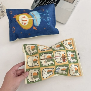 Detail of canvas tissue holders in cartoon blue and checkered cat patterns on a desk