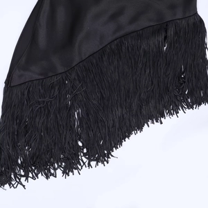 Detail of elegant black satin fabric with long fringe trim on a slim evening gown