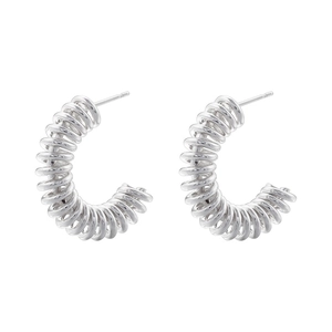 Macro detail of silver-colored C-shaped spiral hoop earrings with a metallic coiled design