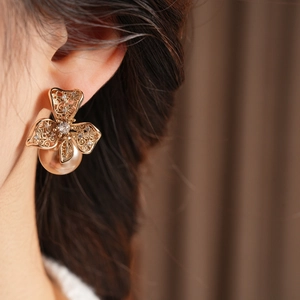 Détail de boucles d'oreilles fleurs dorées avec zircone et perles pendantes élégantes