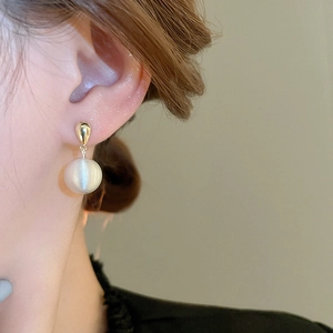 Gros plan de boucles d'oreilles goutte dorées avec perles blanches sur un mannequin