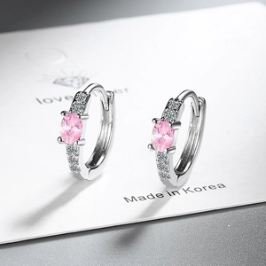 Silver huggie hoop earrings with pink oval zircon and sparkling accents on display