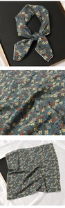 Détail d'un foulard en soie bleu à fleurs avec bordure blanche et nœud papillon