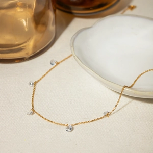 18k gold plated stainless steel necklace with sparkling clear stones on a fabric background